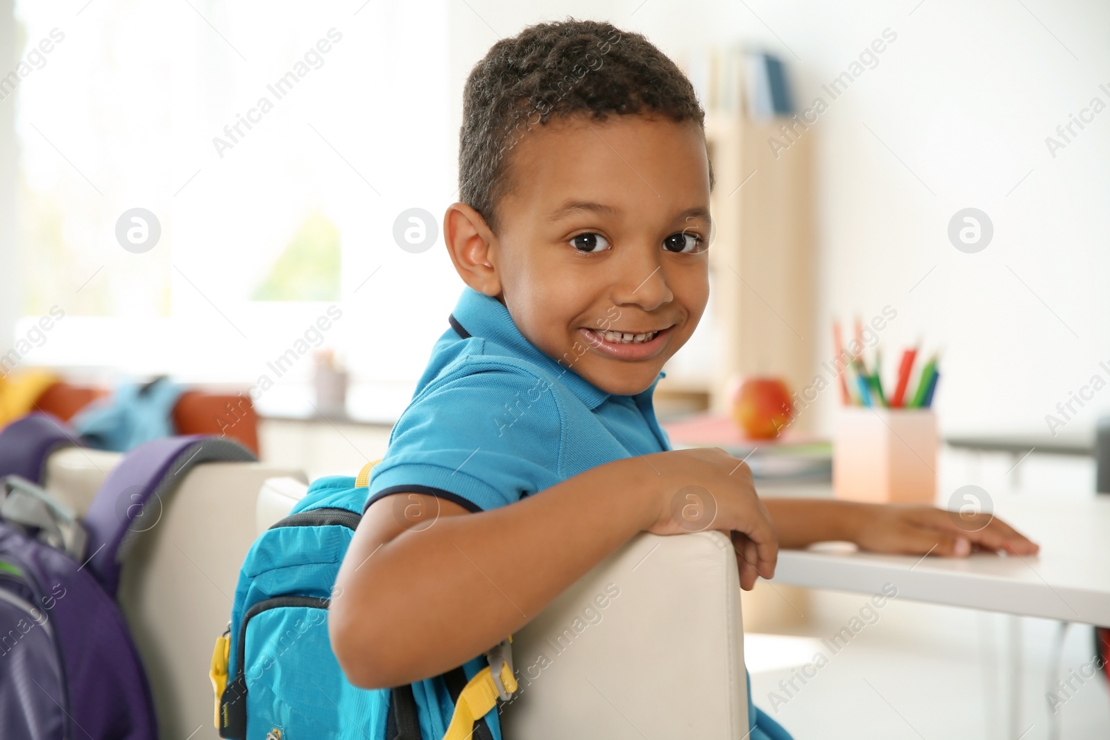 Photo of Cute little child sitting at desk in classroom. Elementary school