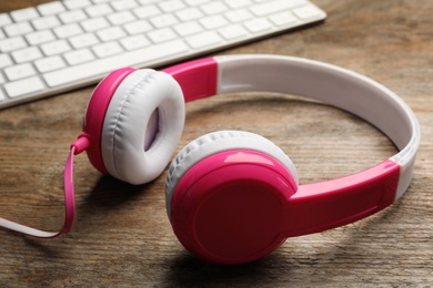 Photo of Modern headphones and computer keyboard on table