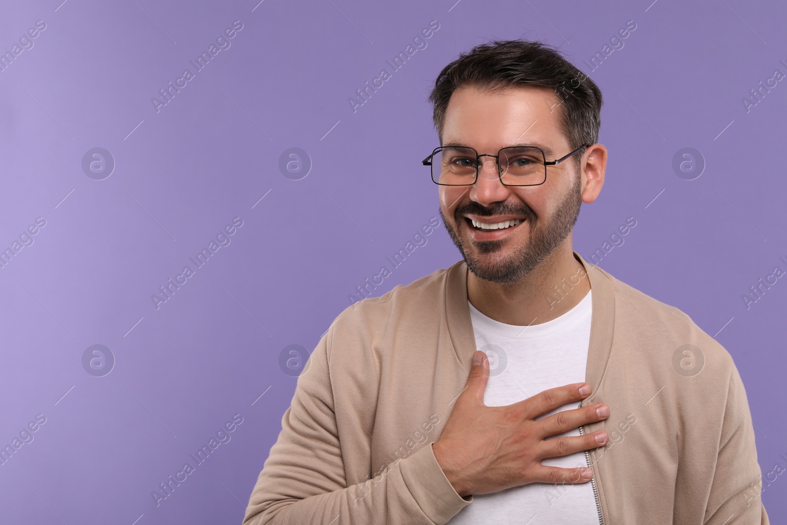 Photo of Portrait of happy man in stylish glasses on violet background, space for text