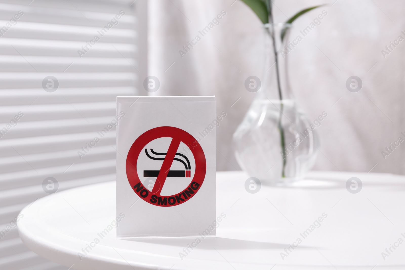 Photo of No Smoking sign on white table indoors, space for text