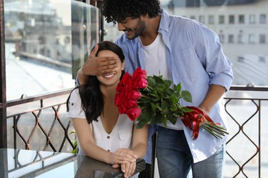 International dating. Handsome man presenting roses to his beloved woman in restaurant