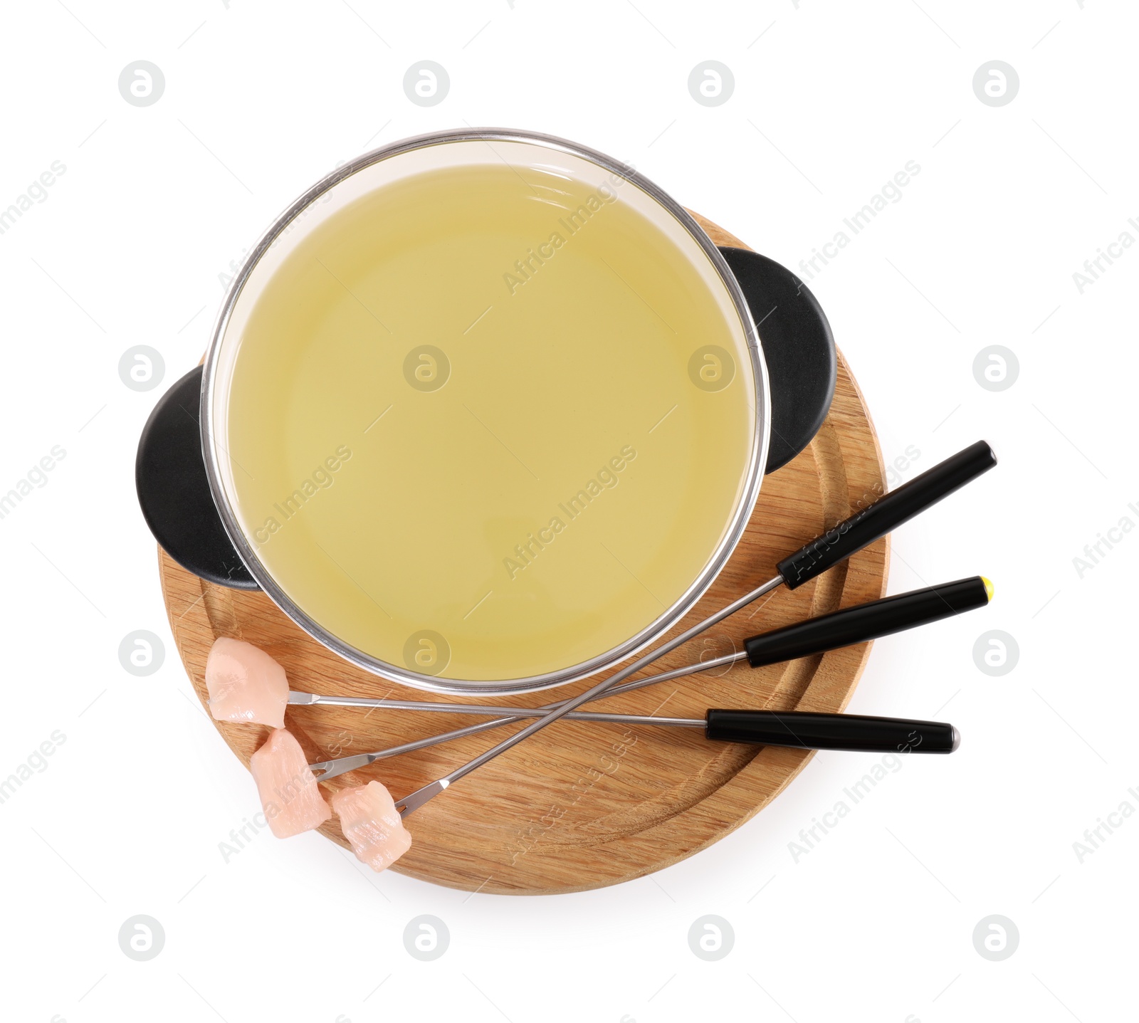 Photo of Oil in fondue pot and forks with pieces of raw meat isolated on white, top view