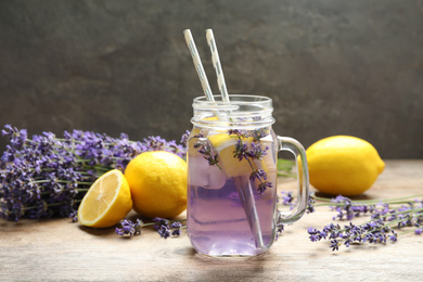 Photo of Fresh delicious lemonade with lavender in masson jar on wooden table