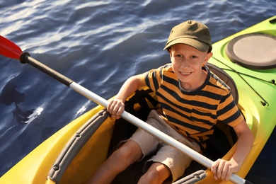 Photo of Happy little boy kayaking on river, above view. Summer camp activity