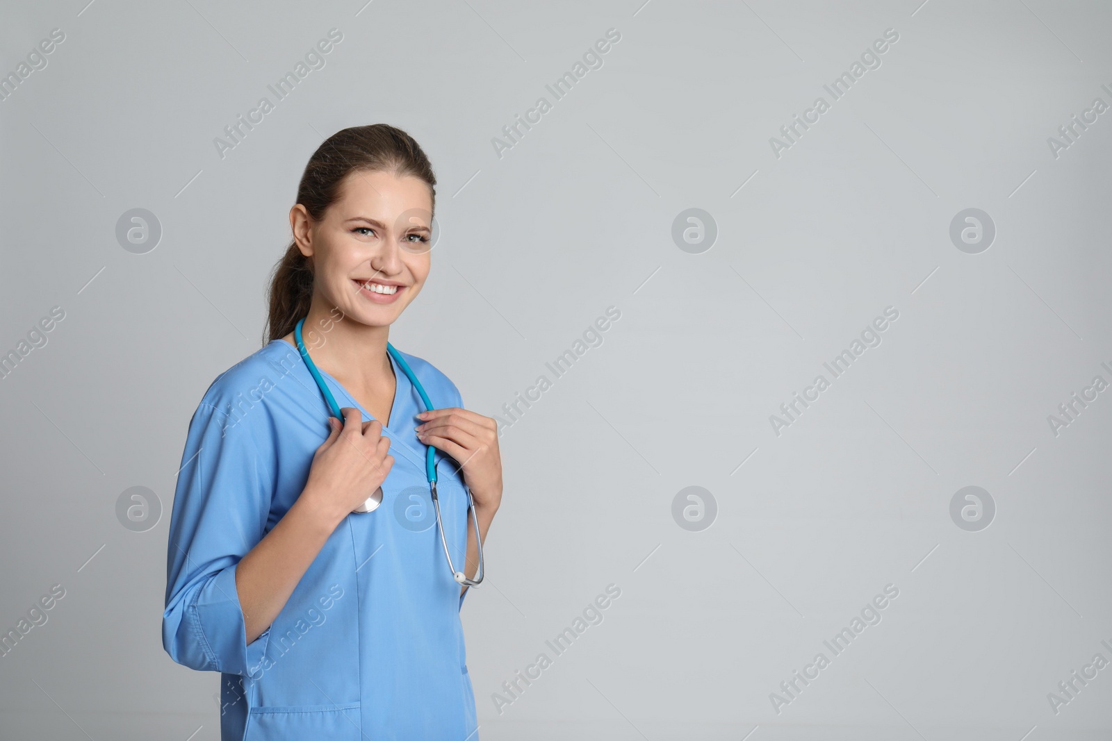 Photo of Portrait of young medical assistant with stethoscope on color background. Space for text