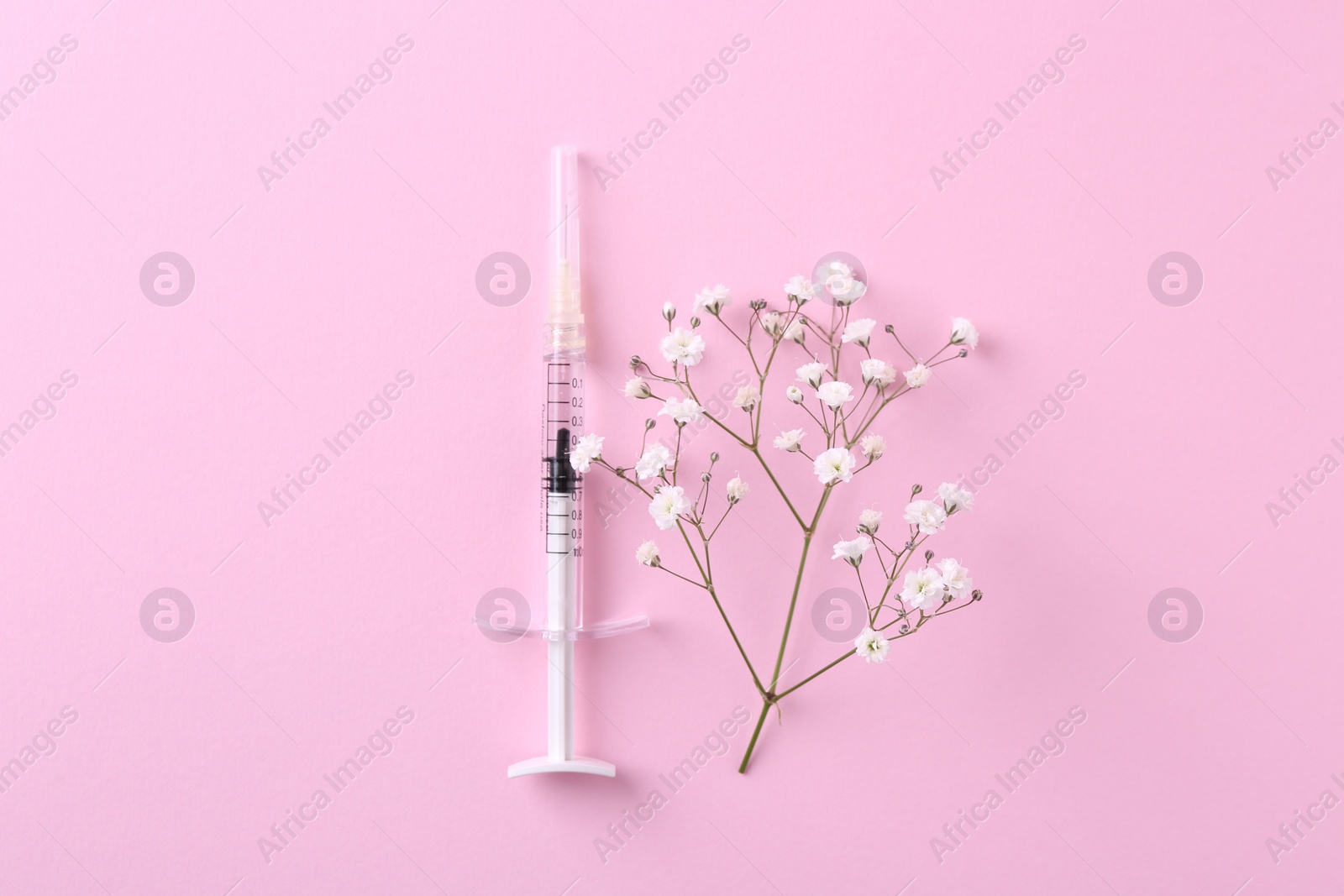 Photo of Cosmetology. Medical syringe and gypsophila on pink background, top view