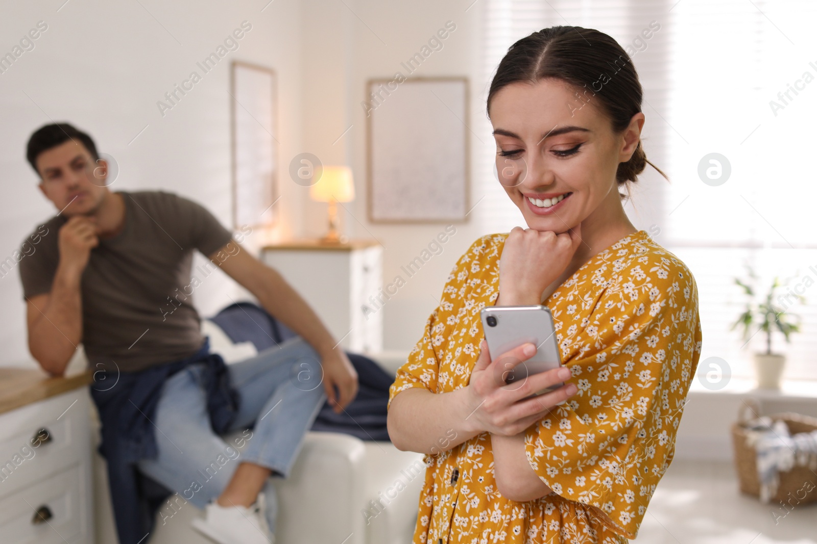 Photo of Woman preferring smartphone over spending time with her boyfriend at home. Jealousy in relationship