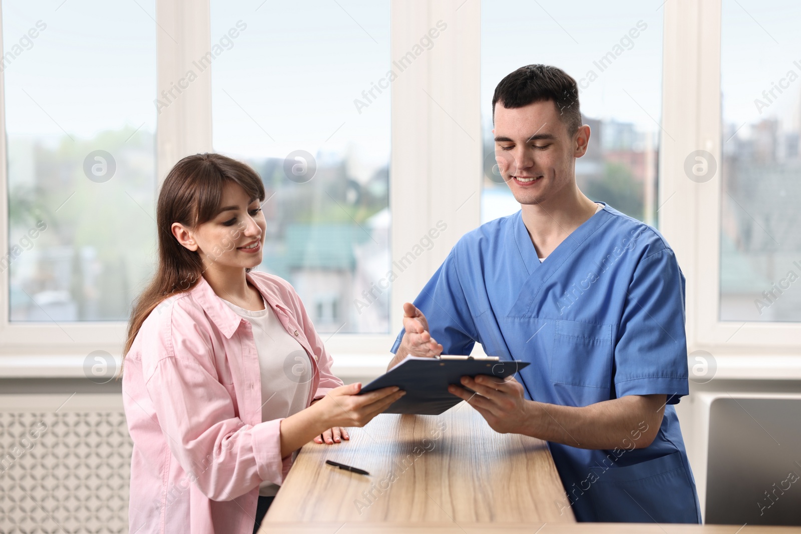 Photo of Smiling medical assistant working with patient at hospital reception