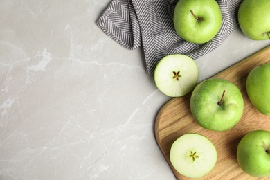 Flat lay composition of fresh ripe green apples on grey stone table, space for text