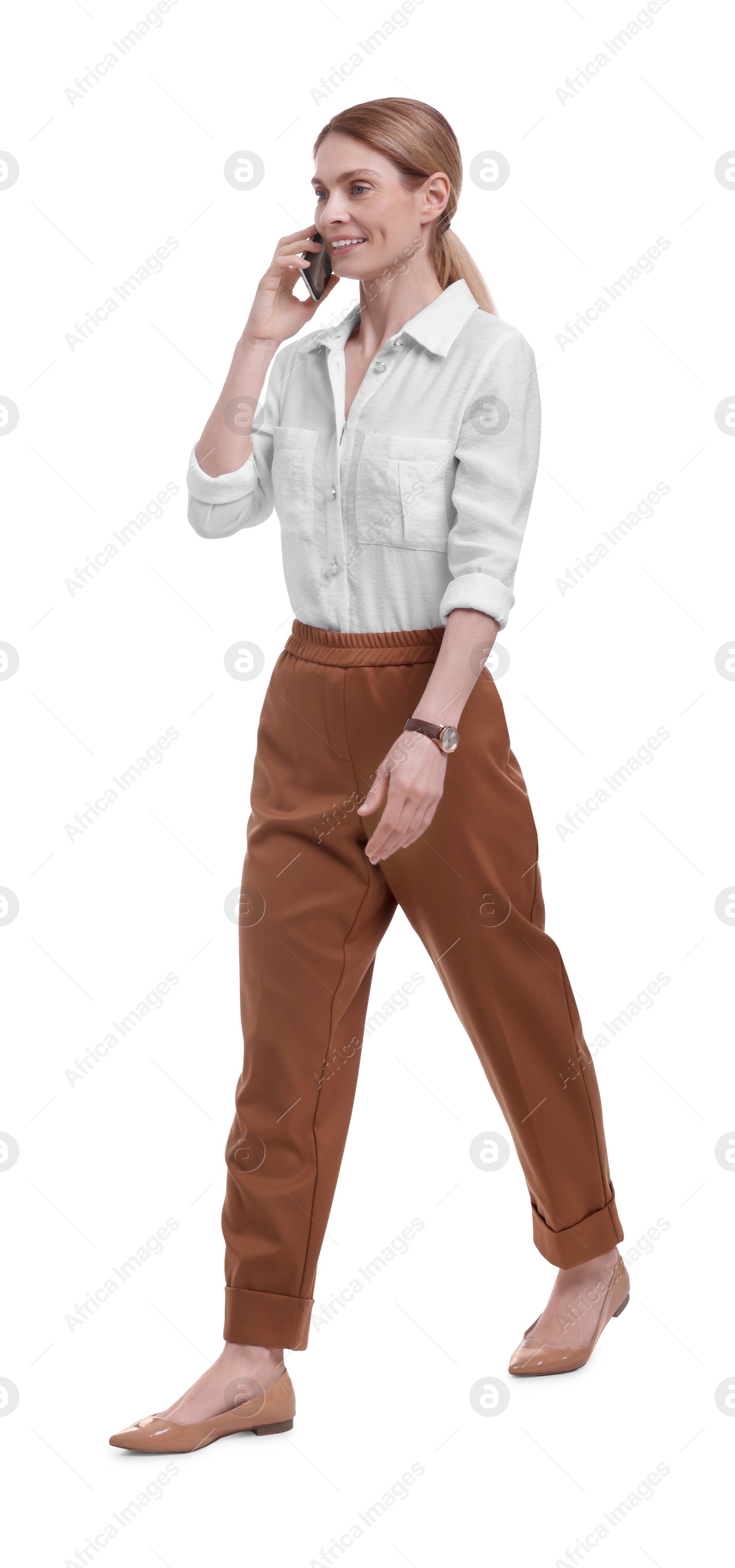 Photo of Beautiful happy businesswoman talking on smartphone while walking against white background