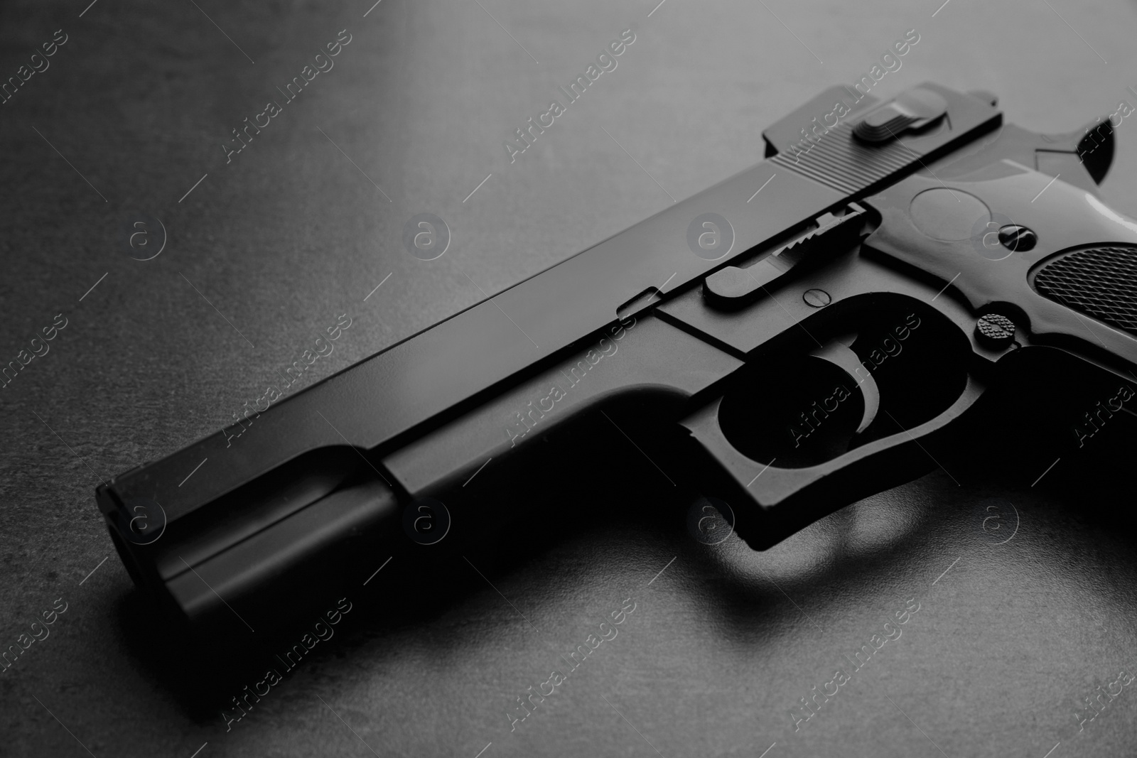 Photo of Black metal gun on stone table, closeup