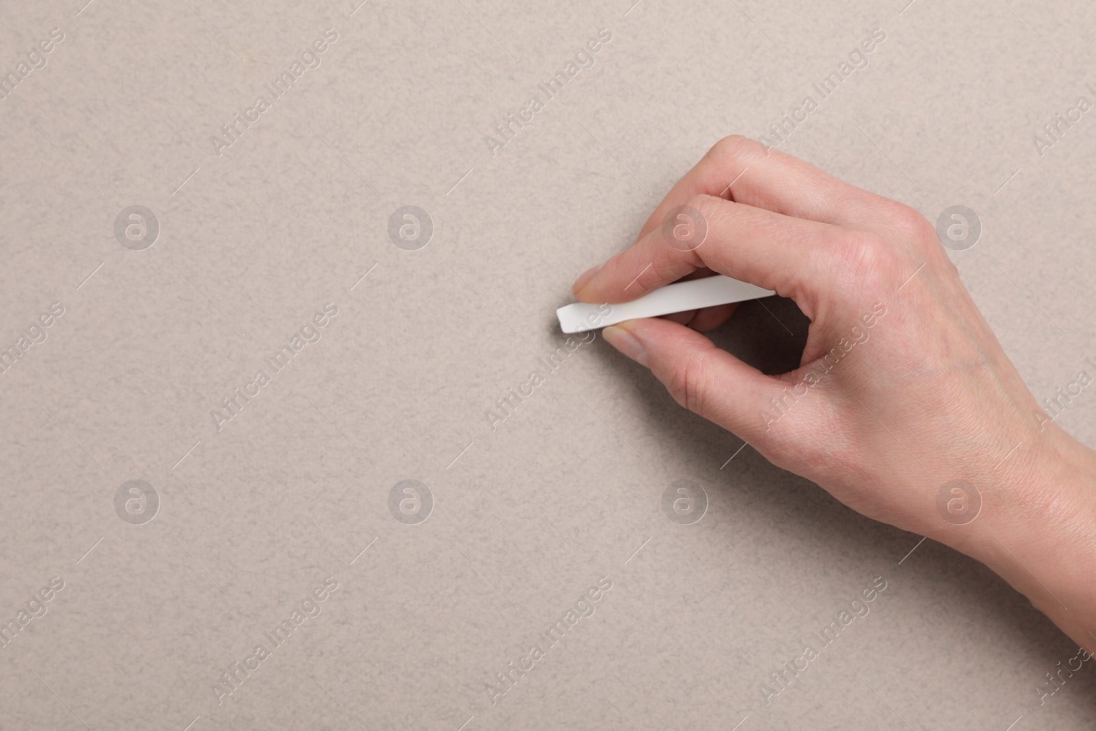 Photo of Woman drawing on grey paper with pastel, top view. Space for text