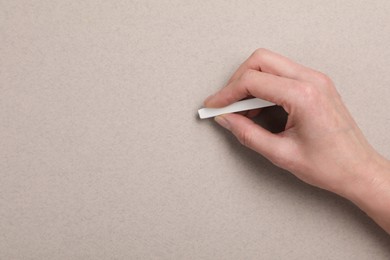 Photo of Woman drawing on grey paper with pastel, top view. Space for text