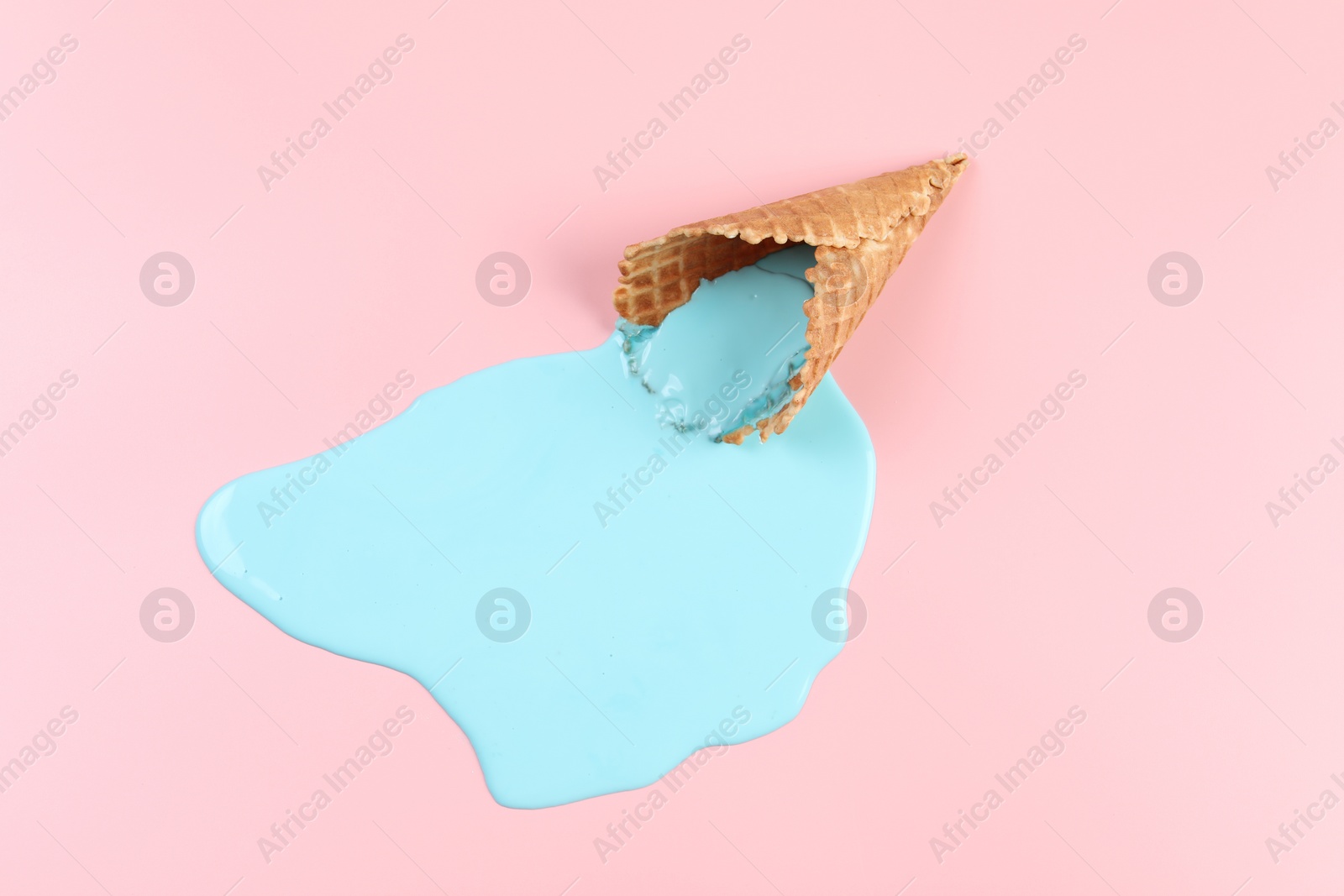 Photo of Melted ice cream and wafer cone on pink background, top view