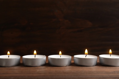 Photo of Small wax candles burning on wooden table