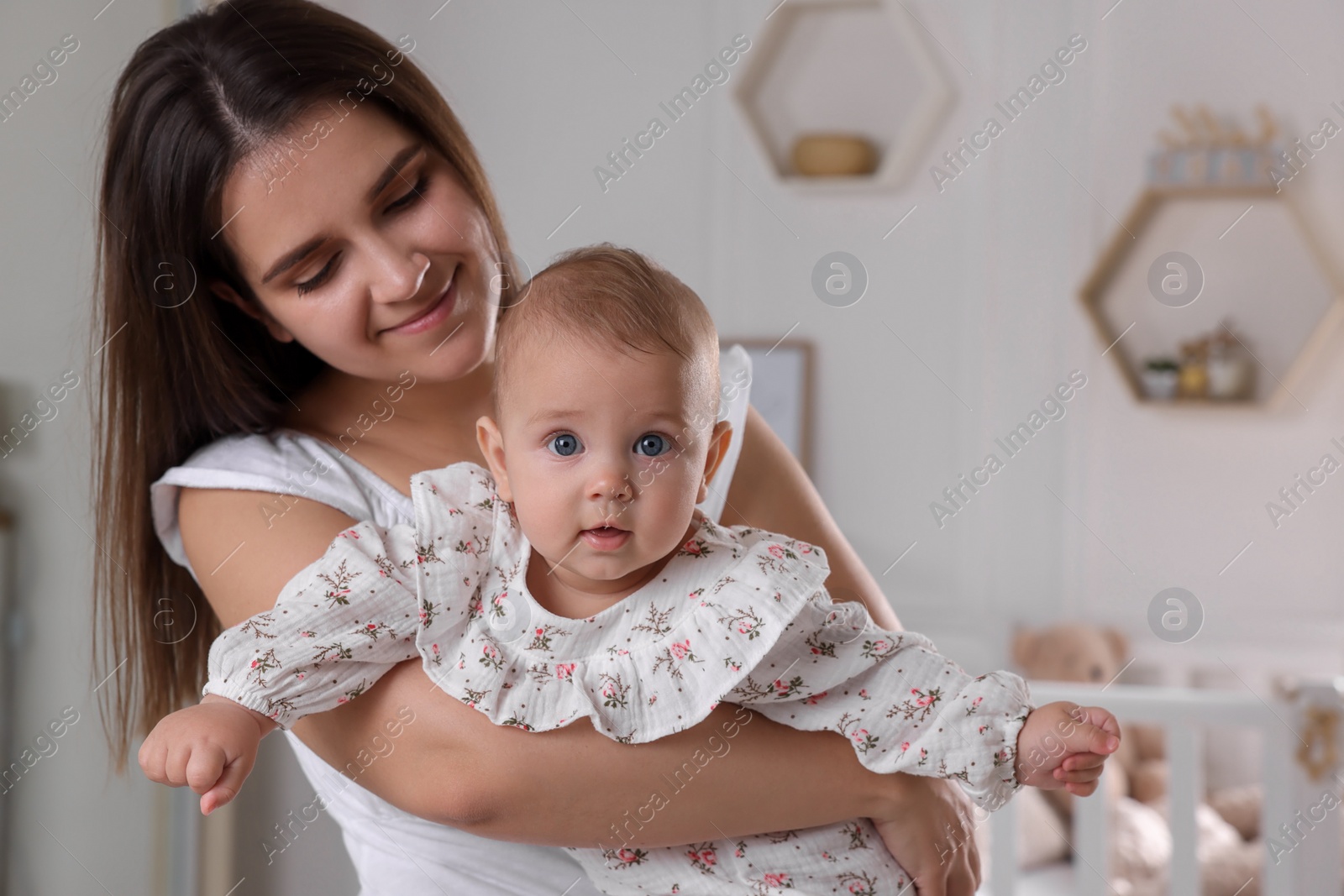 Photo of Happy young mother with her baby daughter in nursery