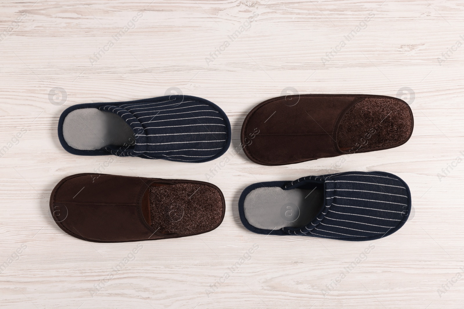 Photo of Different stylish slippers on white wooden floor, flat lay