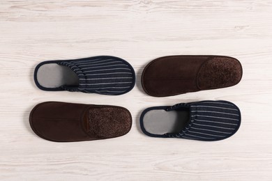 Different stylish slippers on white wooden floor, flat lay