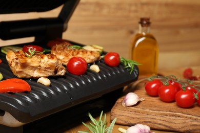 Photo of Electric grill with different products on wooden table