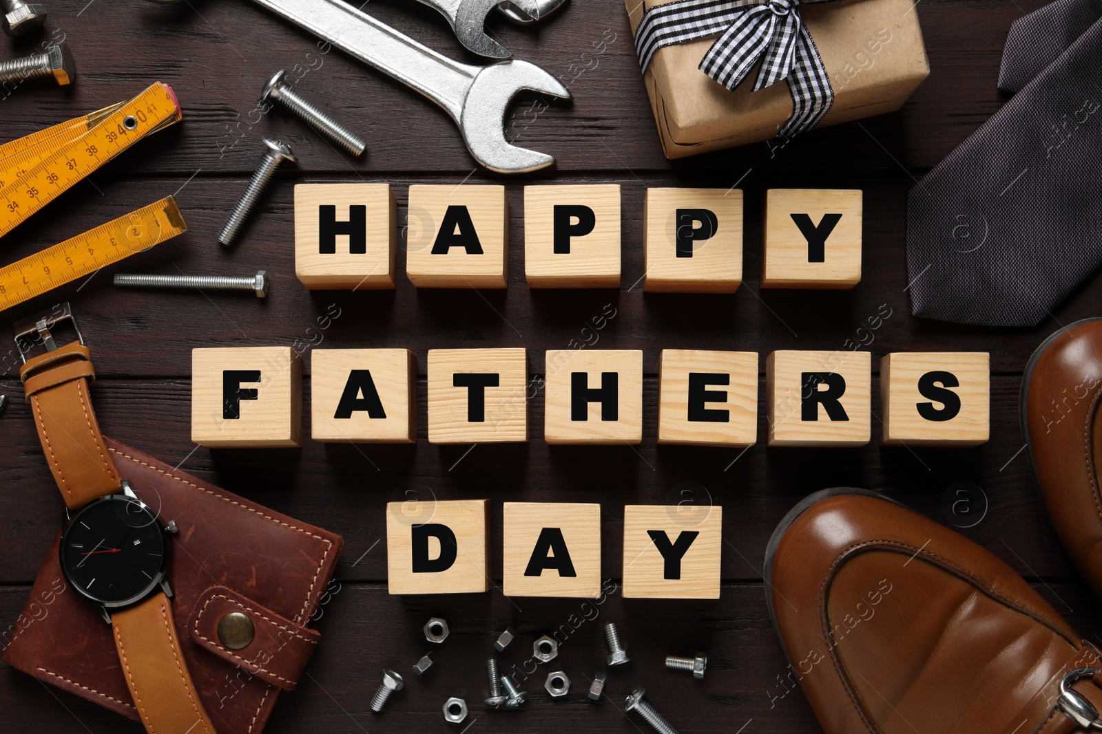 Photo of Cubes with phrase HAPPY FATHER'S DAY, 
different tools and male accessories on wooden background, flat lay