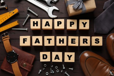 Photo of Cubes with phrase HAPPY FATHER'S DAY, 
different tools and male accessories on wooden background, flat lay