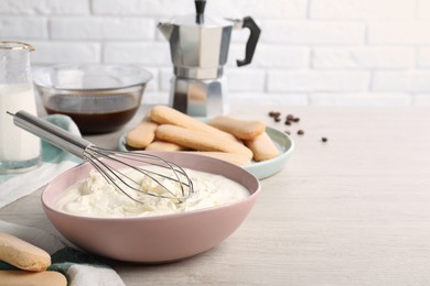 Photo of Bowl with mascarpone cream on white wooden table, space for text. Making tiramisu cake