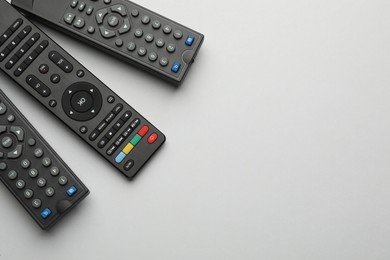 Remote controls on light grey background, flat lay. Space for text