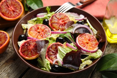 Photo of Bowl of delicious sicilian orange salad on wooden table, closeup