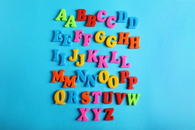 Photo of Many colorful magnetic letters on light blue background, flat lay. Alphabetic order
