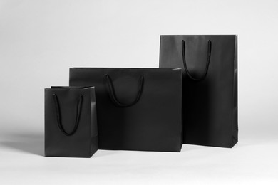 Three black paper shopping bags on grey background