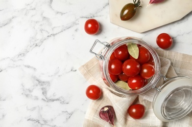 Photo of Pickling jar with fresh ripe cherry tomatoes on white marble table, flat lay. Space for text