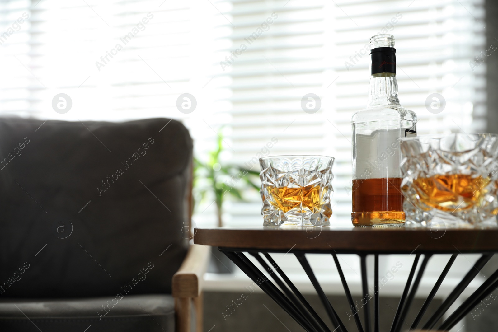 Photo of Glasses and bottle of whiskey on table indoors. Space for text