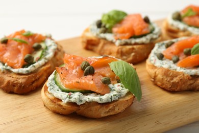 Tasty canapes with salmon, capers, cucumber and sauce on table, closeup