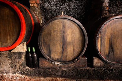 Photo of Wooden barrels with alcohol drinks in cellar