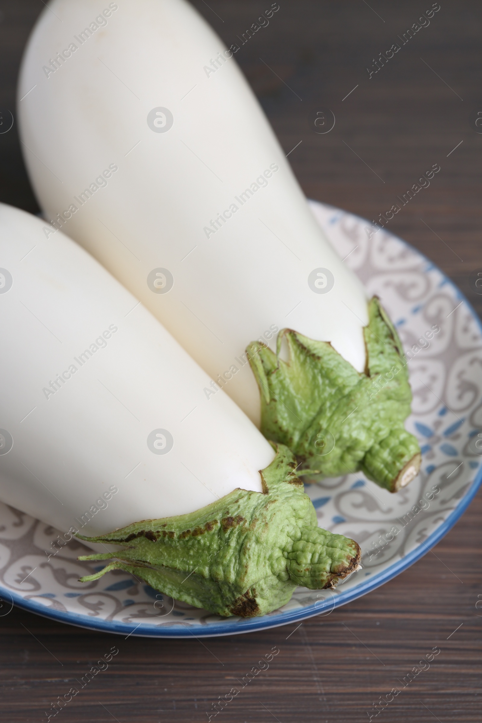 Photo of Two fresh white eggplants on wooden table, closeup