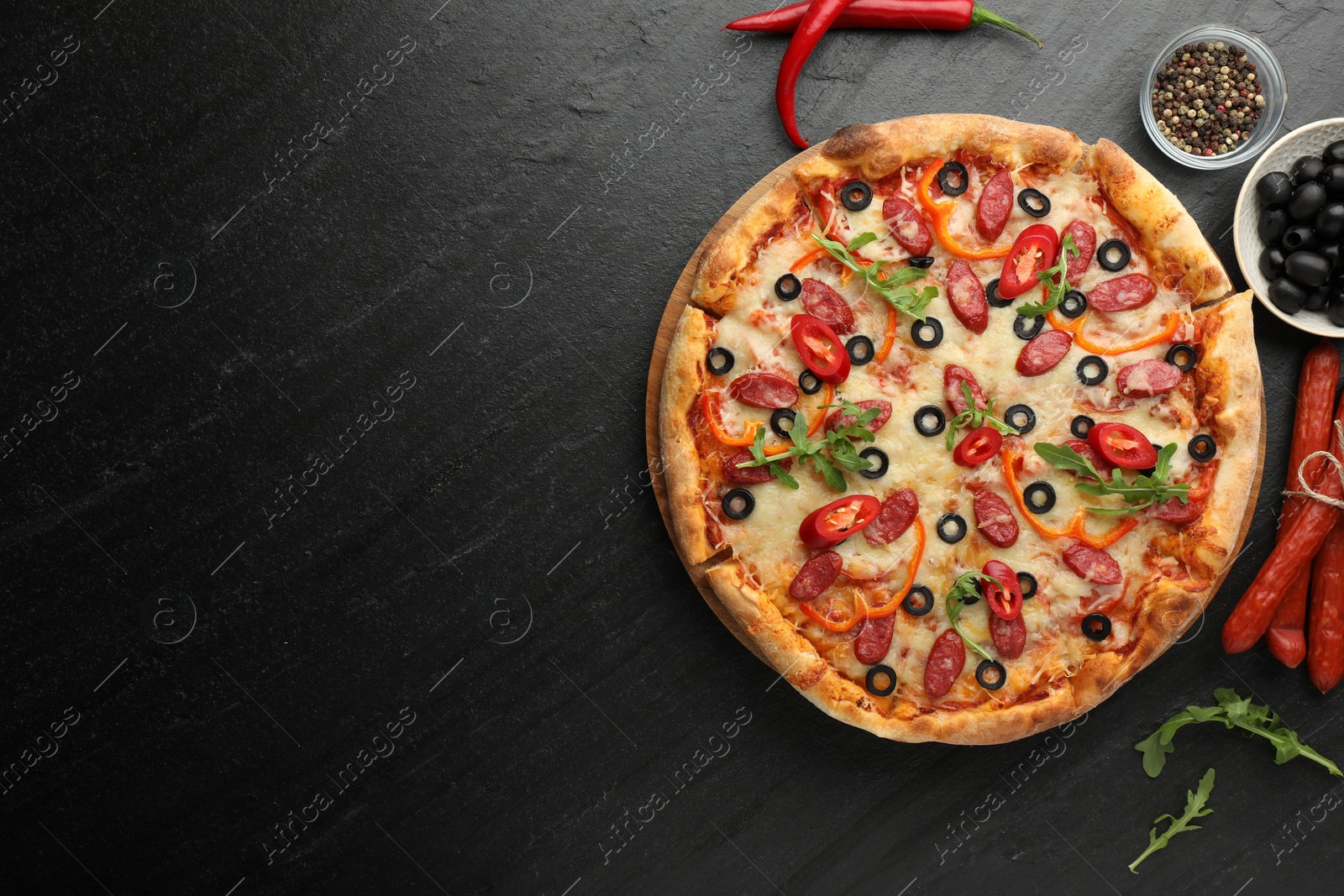 Photo of Tasty pizza and ingredients on black table, top view. Space for text