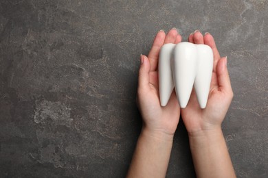 Photo of Woman with tooth model on grey background, top view. Space for text