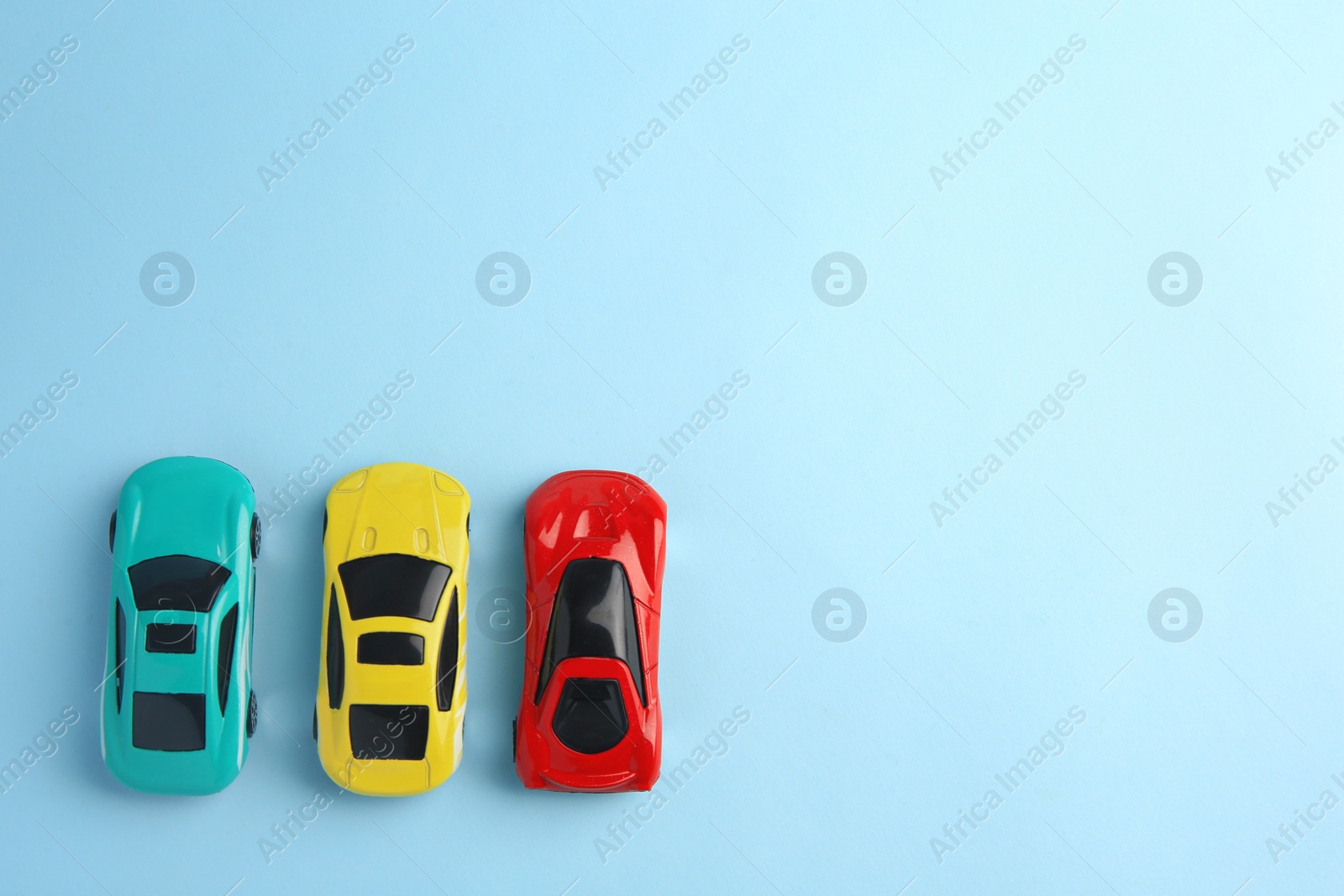 Photo of Different bright cars on light blue background, flat lay with space for text. Children`s toys