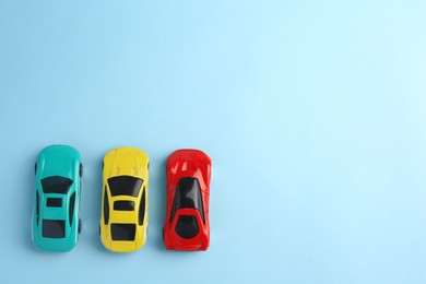 Different bright cars on light blue background, flat lay with space for text. Children`s toys