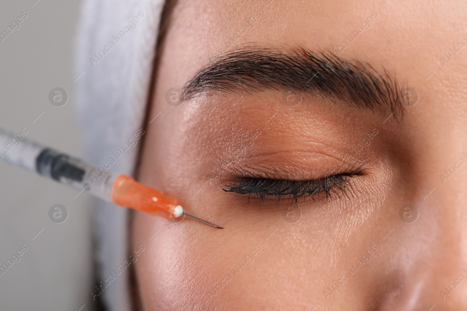 Photo of Young woman getting facial injection on light grey background, closeup. Cosmetic surgery