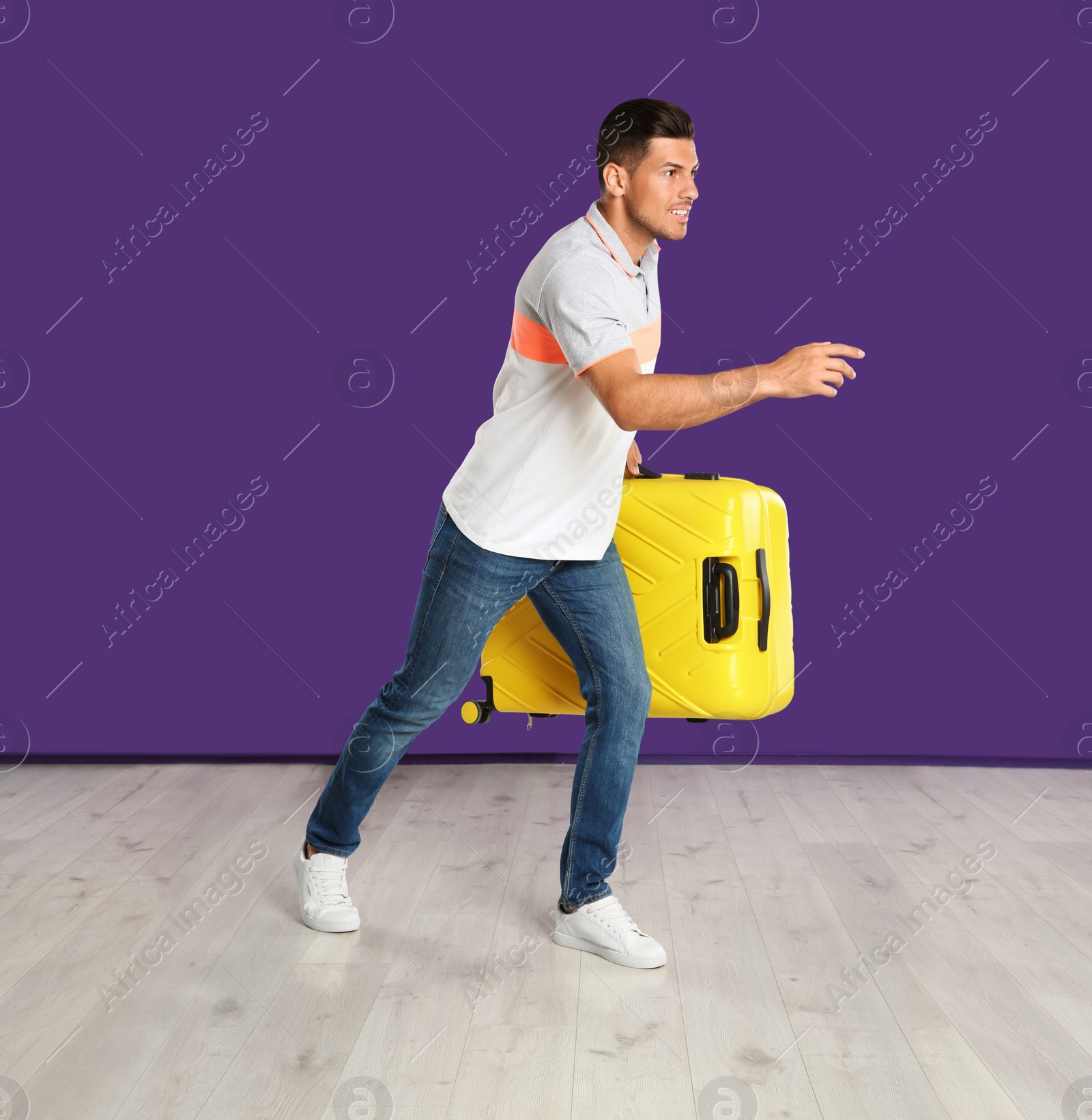 Photo of Man with suitcase for summer trip running on purple background. Vacation travel