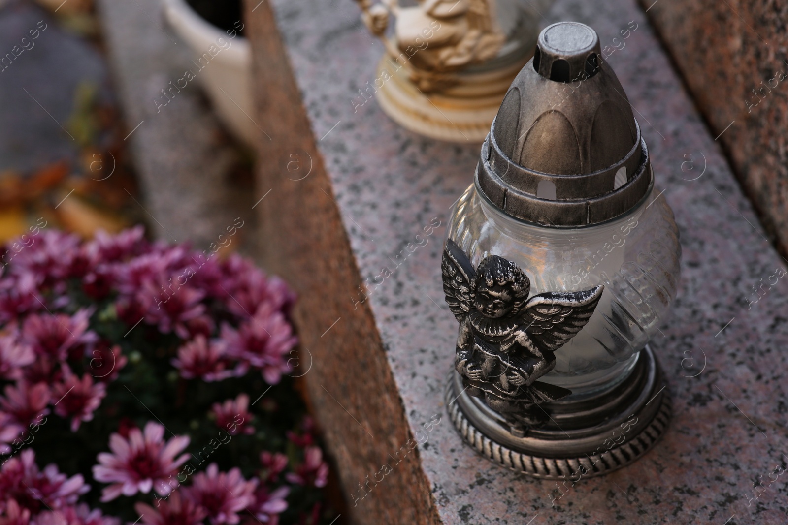 Photo of Grave lanterns and flowers on granite surface in cemetery