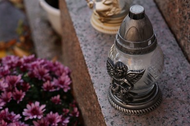 Photo of Grave lanterns and flowers on granite surface in cemetery