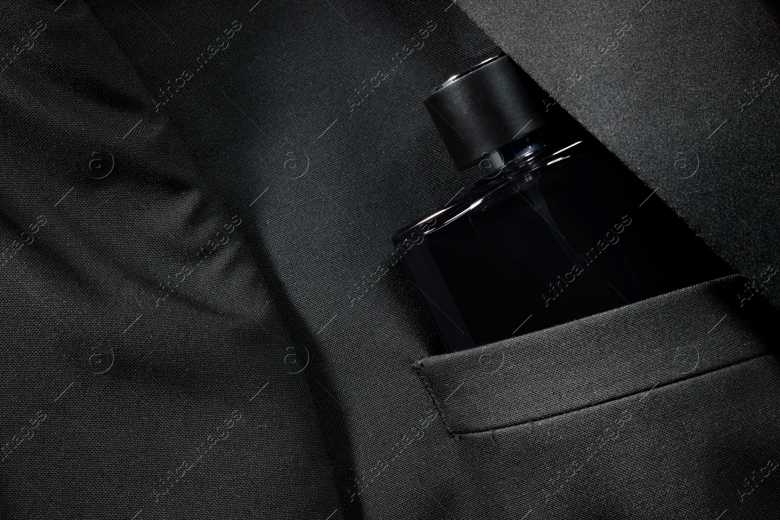 Photo of Luxury men's perfume in breast pocket of black jacket, top view. Space for text