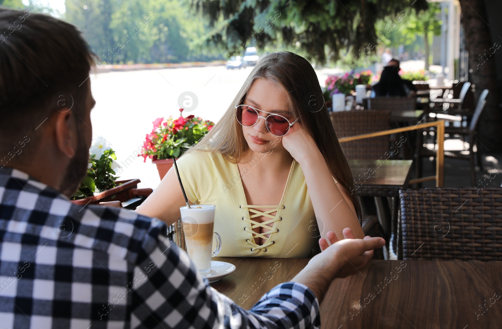 Photo of Young woman having boring date with guy in outdoor cafe