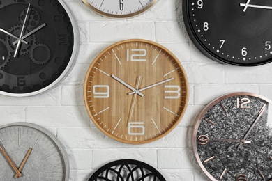 Different analog clocks hanging on white wall. Time of day