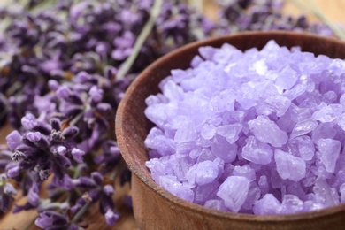 Photo of Wooden bowl of natural lavender bath salt and flowers on table, closeup with space for text. Cosmetic product
