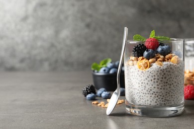 Photo of Delicious chia pudding with berries, granola and mint on grey table, space for text