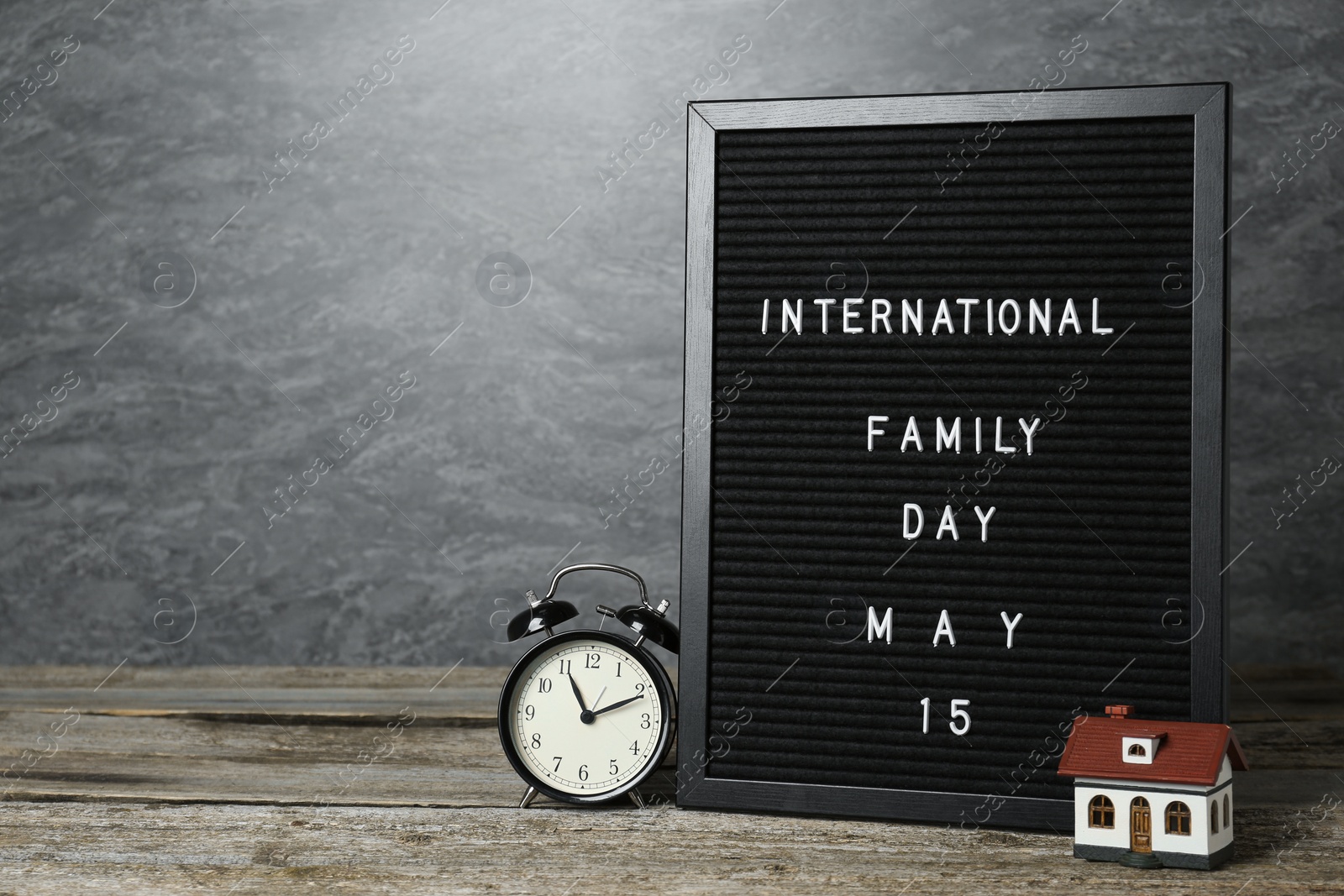 Photo of Happy Family Day. Black letter board with text, clock and house model on wooden table. Space for design