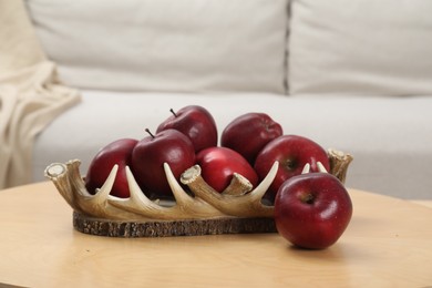 Red apples on wooden coffee table in room